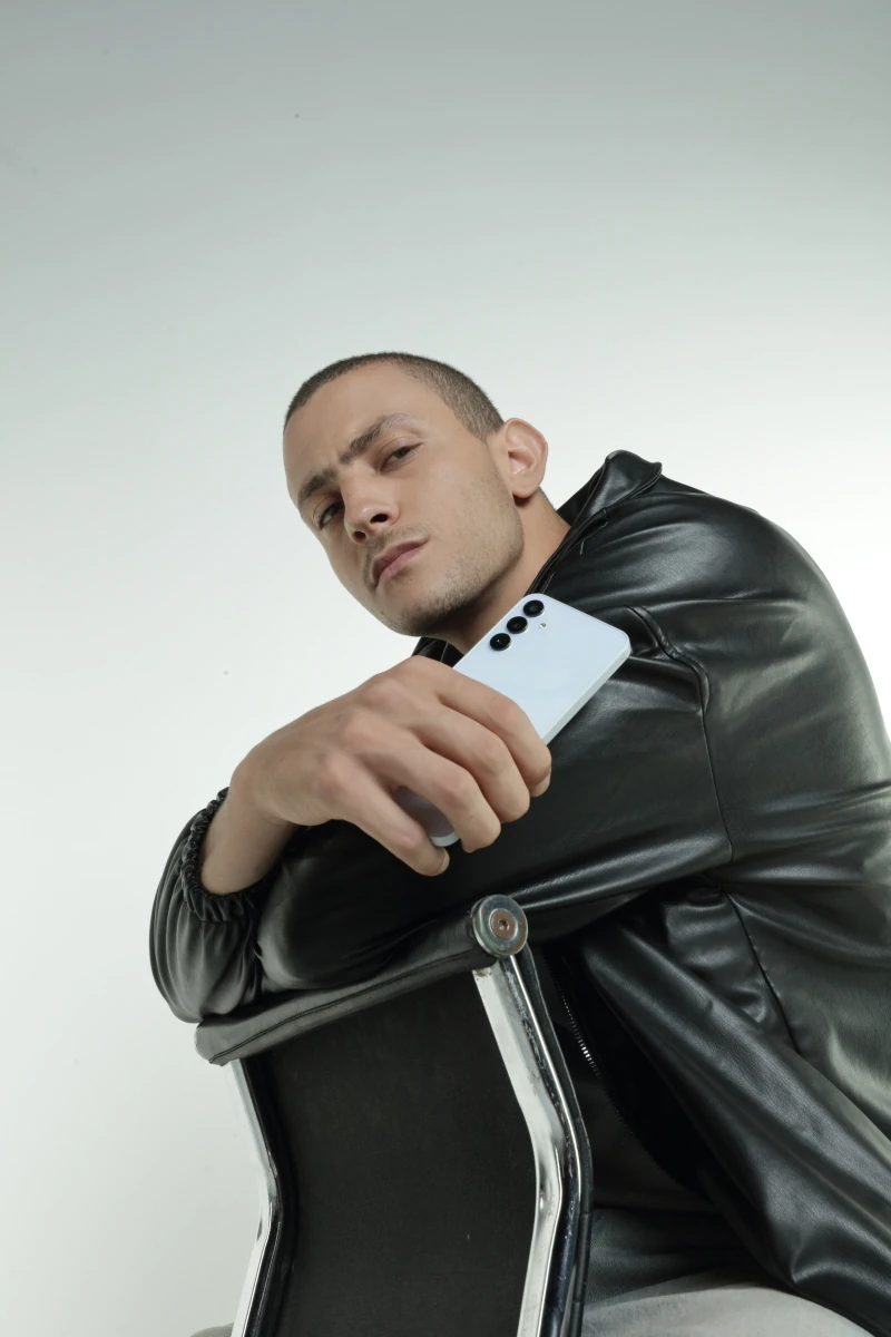 Fares Abdeddayem in a leather jacket holding the Galaxy A15